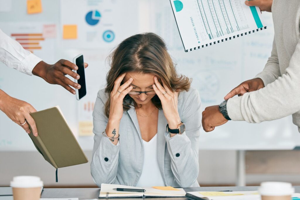 Conséquence de la ménopause au travail : impacts et astuces 4 Une femme surmenée est au bureau et se tient la tête pour illustrer les conséquences de la ménopause au travail