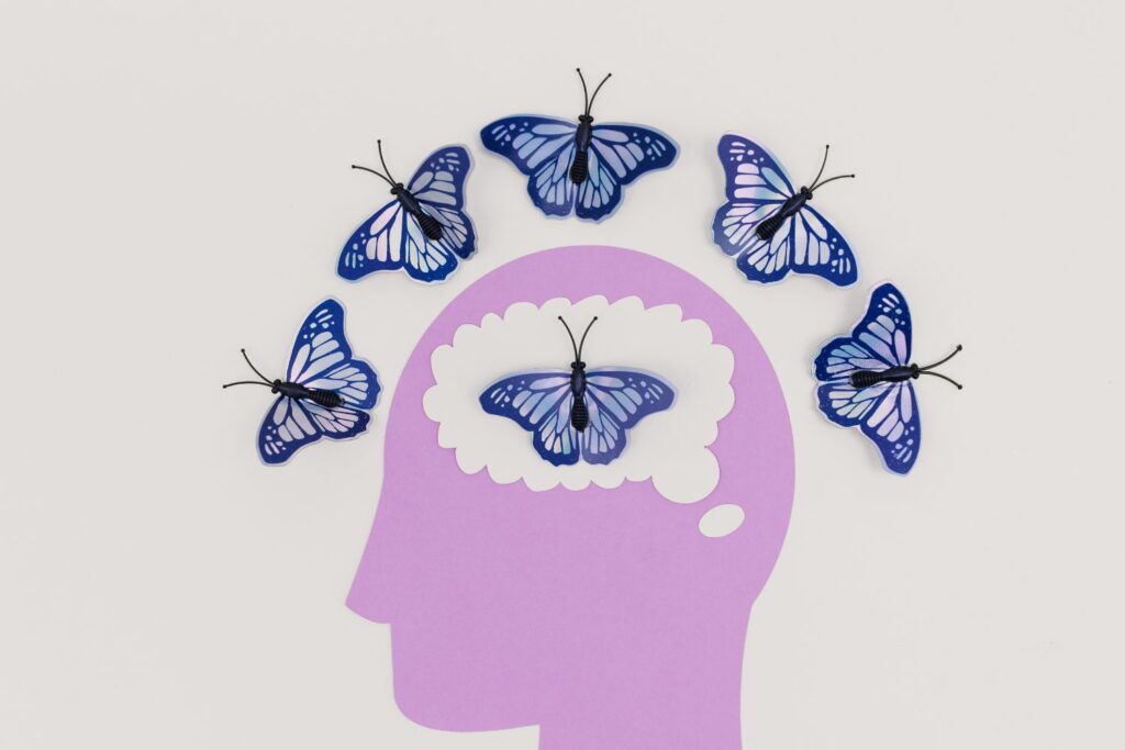 Conséquence de la ménopause au travail : impacts et astuces 1 Illustration d'une tête humaine avec des papillon à l'intérieur et autour pour illustrer les conséquences de la ménopause au travail