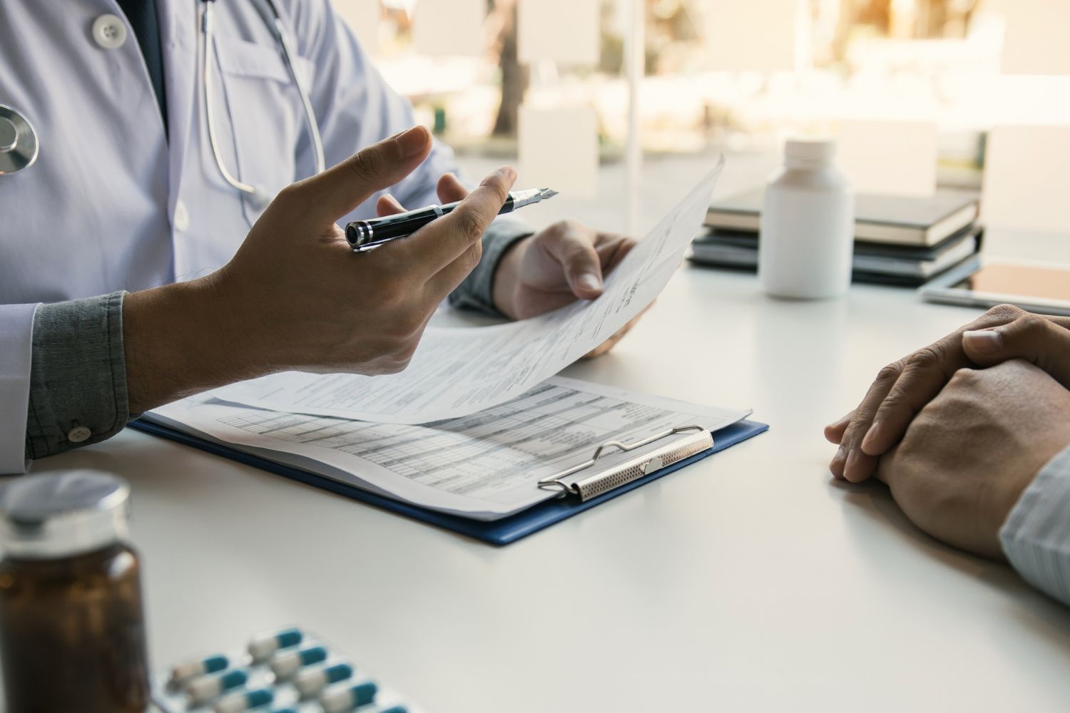 Les mains d'un médecin à une table assis en face d'un patient pour illustrer les conséquences de la ménopause au travail