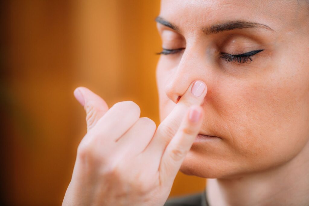 Respiration alternée ménopause : mini-routine zen anti-stress 4 Une femme presse une de ses narine avec son annulaire pour faire un exercice de respiration alternée menopause