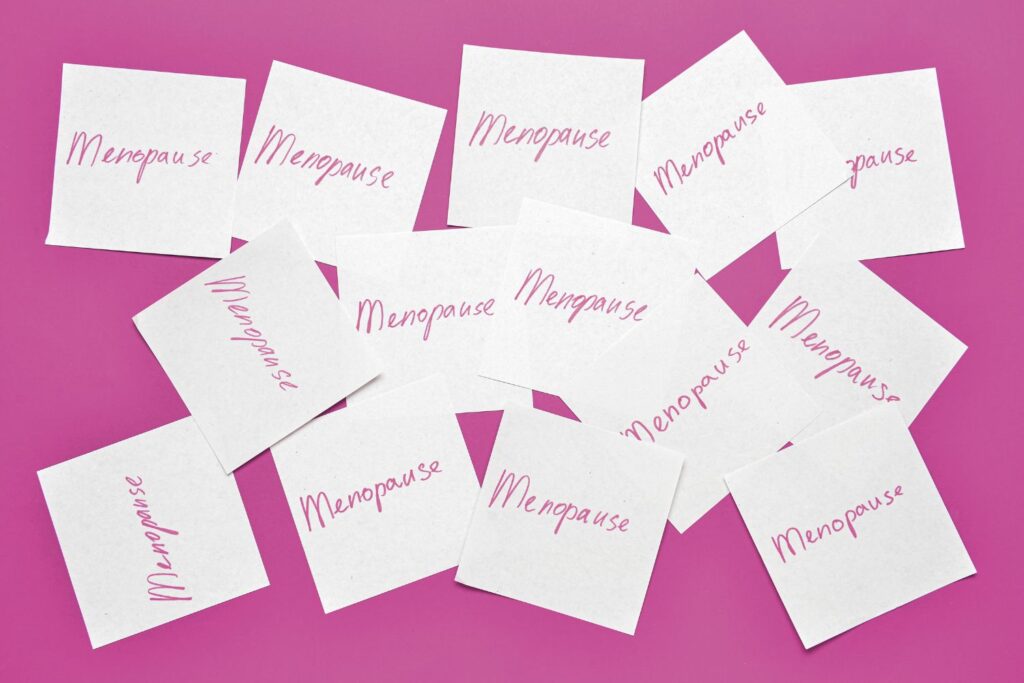 des etiquettes éparpillées sur un fond rose pour illustrer l'article menopause guide complet