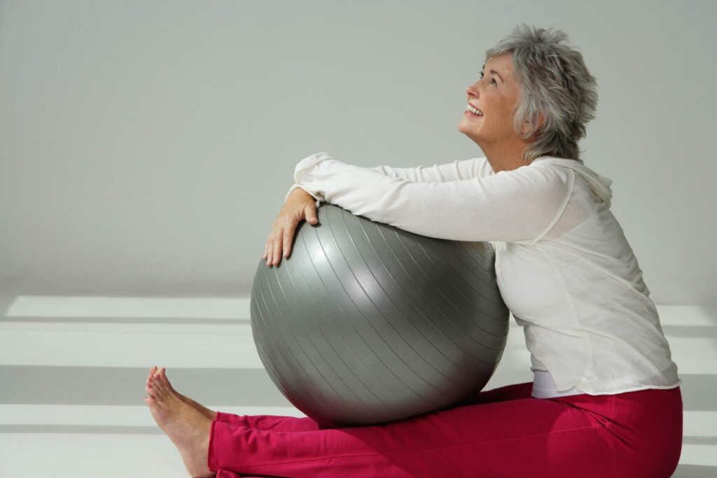 Ménopause : guide complet pour comprendre et mieux vivre cette étape de vie 7 une femme d'environ 60 ans tien un ballon pilate pour illustrer l'article menopause guide complet