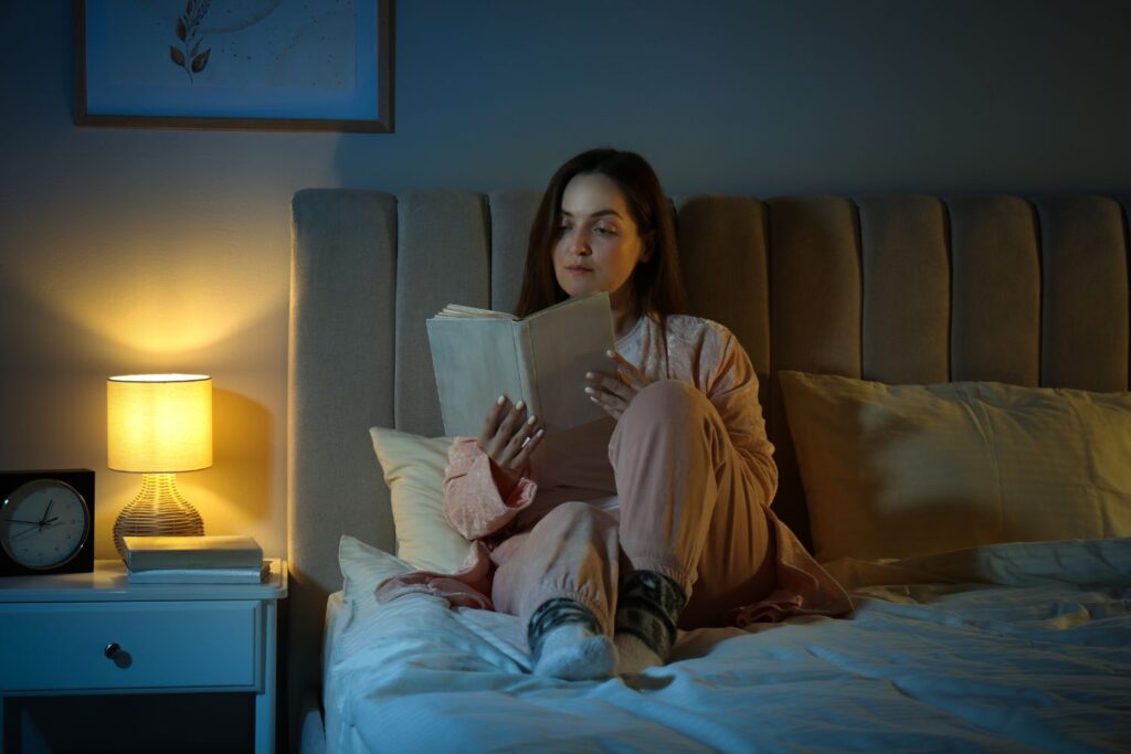 Ménopause : guide complet pour comprendre et mieux vivre cette étape de vie 9 une femme lit dans sa chambre sur son lit le soir pour illustrer l'article menopause guide complet