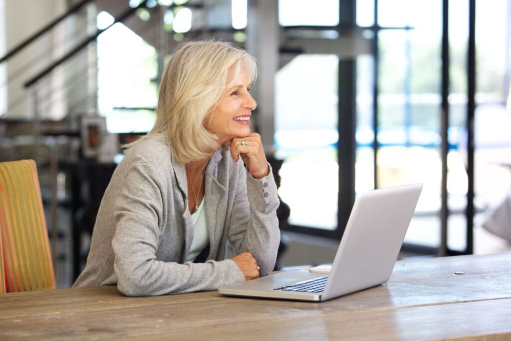 Ménopause : guide complet pour comprendre et mieux vivre cette étape de vie 13 une femme blonde assise devant son ordinateur pour illustrer l'article menopause guide complet