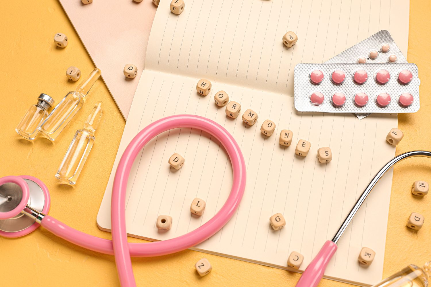 une photo avec des, des comprimés et le fil d'un stéthoscope sur une table avec le mot HORMONES écrit pour illustrer l'article traitement hormonal substitutif