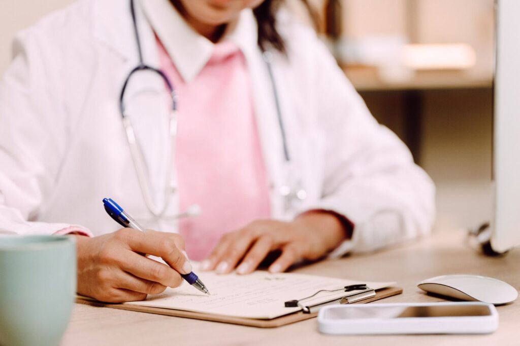 Ménopause et troubles du sommeil : pourquoi nos nuits partent en vrille (et comment les récupérer) 30 une medecin femme en train d'écrire pour illustrer l'article traitement hormonal substitutif