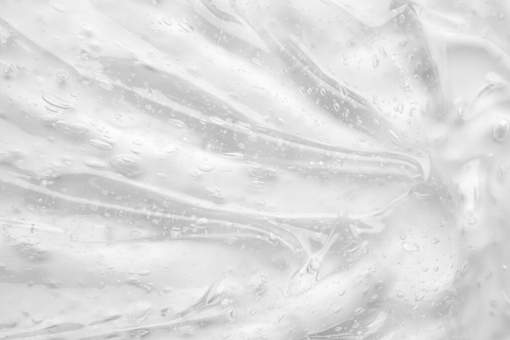 Un liquide gélatineux transparent sur un fond blanc pour illustrer l'article comment choisir son lubrifiant à la ménopause.