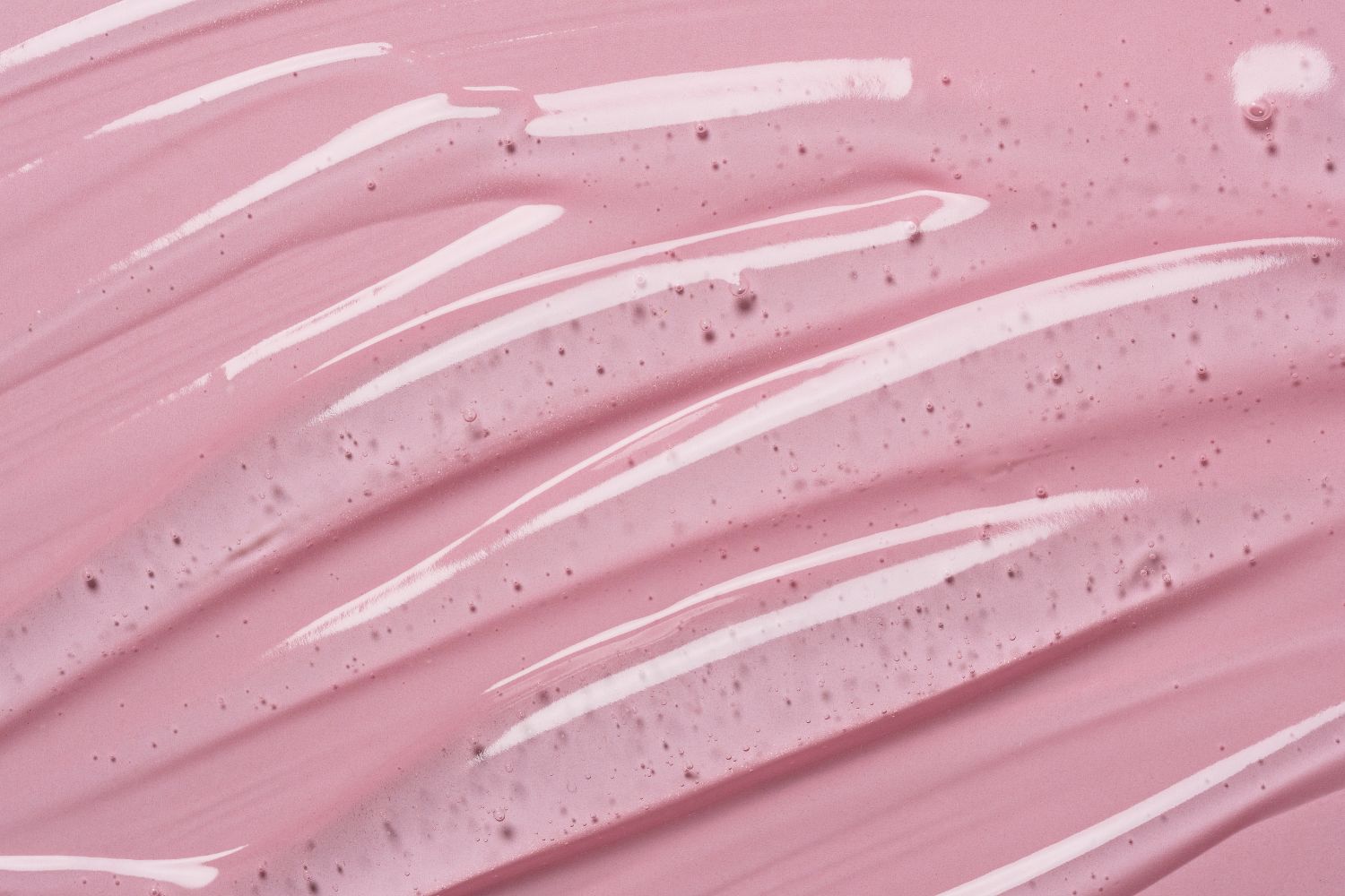 Un liquide gélatineux transparent sur un fond rose pour illustrer l'article comment choisir son lubrifiant à la ménopause.