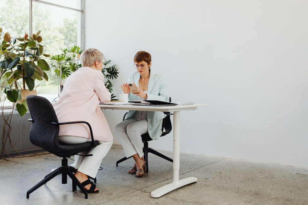 Deux femme face à face autour d'un bureau pour illustrer l'article comment parler de la ménopause au travail