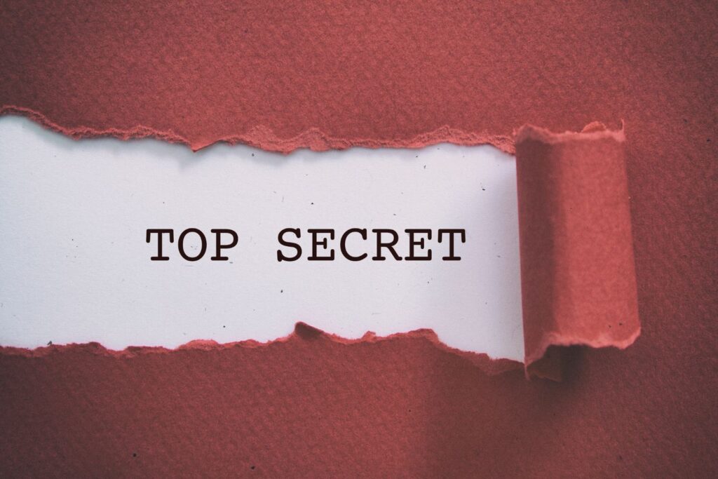 Les mots top secret sous une feuille de papier déchirée rose pour illustrer l'article comment parler de la ménopause au travail