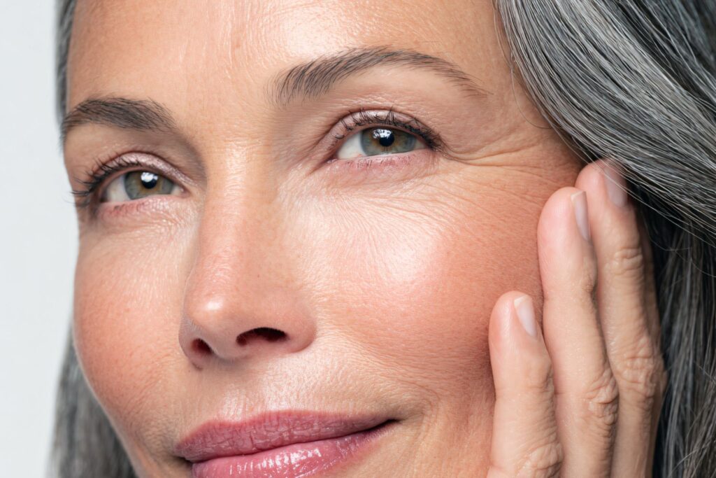 Le visage d'une femme la cinquantaine en gros pman avec les yeux vert cheveux gris et une beau saine pour illustrer l'article peau sèche à la ménopause