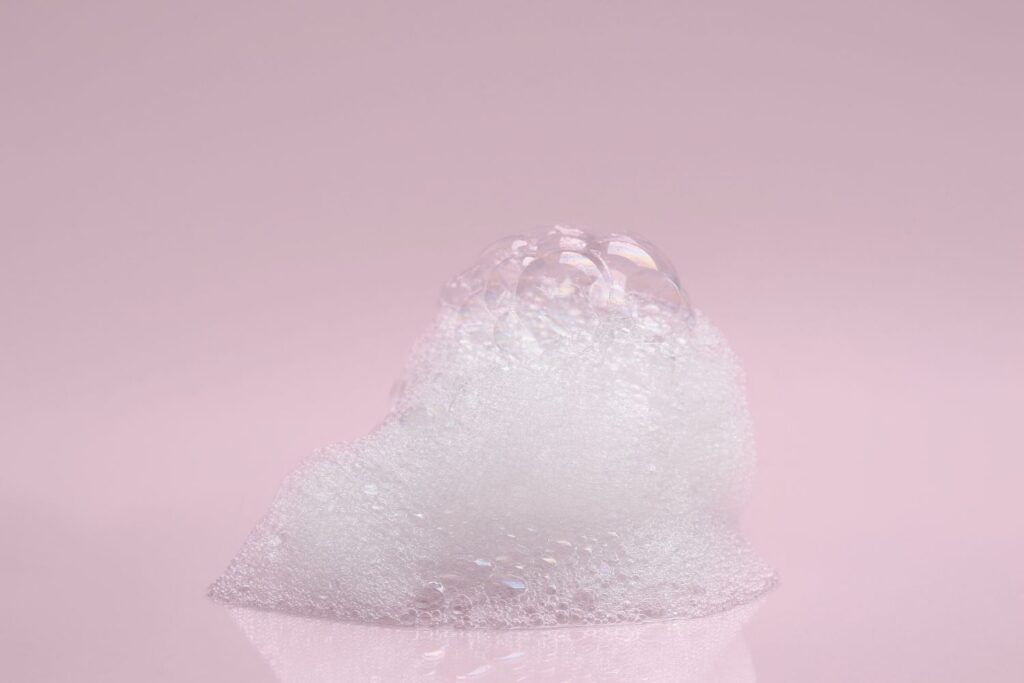 De la mousse de savon sur un fond rose pour illustrer l'article peau sèche à la ménopause