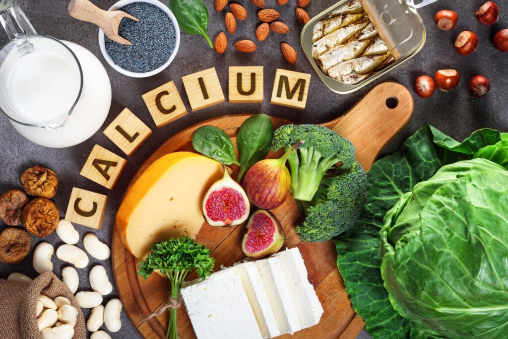 Le mot calcium en lettre de bois sur une table au milieu d'aliments contenants du calcium pour illustrer l'article quoi manger à la ménopause