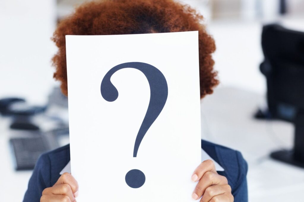 Une femme se tient devant nous avec une pancarte marquée d'un point d'interrogation devant le visage pour illustrer l'article sperme de saumon en injection.