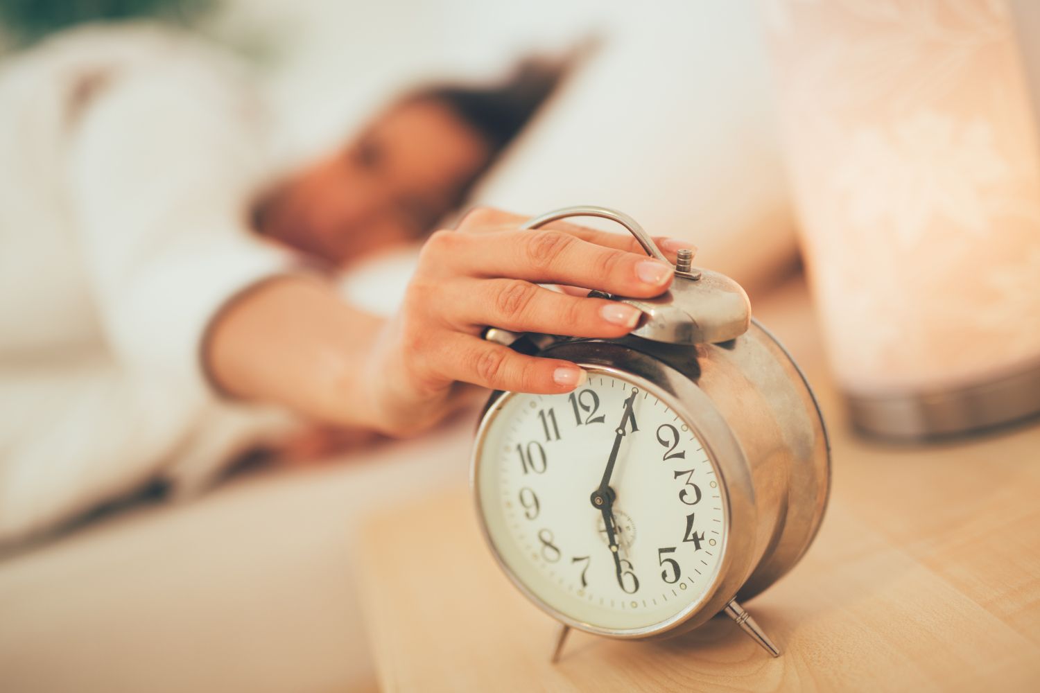 Un main de femme qui appuie sur le réveil pour illustrer l'article sommeil et ménopause