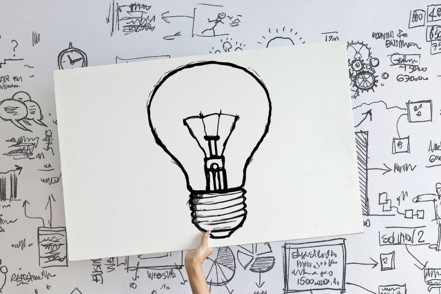 Le dessin d'une ampoule au crayon noir sur un fond blanc tenu par une main de femme pour illustrer le sommeil et ménopause